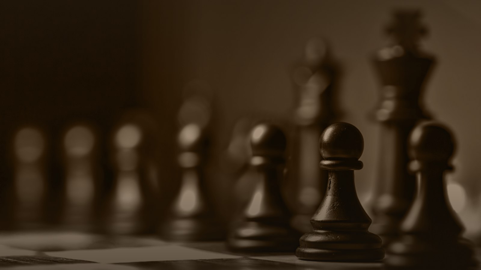 Sepia-toned photo of dark chess pieces on a board